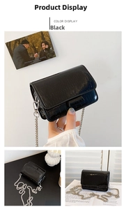Detail of black crocodile texture bag featuring a glossy finish and silver metal chain strap