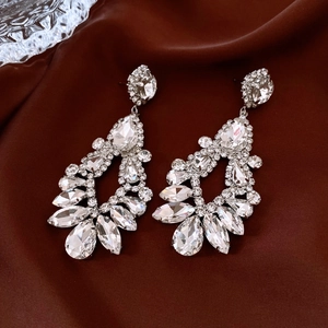 Détail de boucles d'oreilles pampilles en argent et strass sur fond de soie foncée