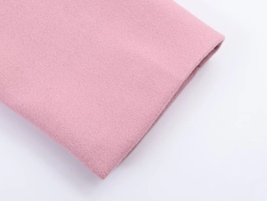 Macro shot of soft pink wool fabric texture and fine fiber detail on an oversized blazer
