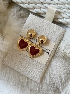 Detail of vintage heart earrings with burgundy enamel and braided gold-plated borders