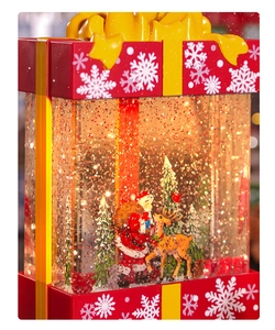 Close-up of red Christmas gift box water globe with Santa and reindeer scenes
