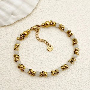 Elegant gold stainless steel beaded bracelet with white translucent stones on white surface