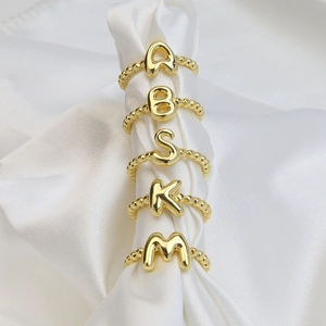 Adjustable 18K gold letter rings with bubble bead bands A B S K M on white silk