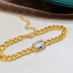 Close-up of gold chunky chain bracelet with rectangular emerald green cubic zirconia
