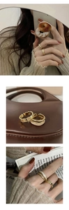 Detailed close-up of a two-piece gold ring set featuring white shell inlay on a hand