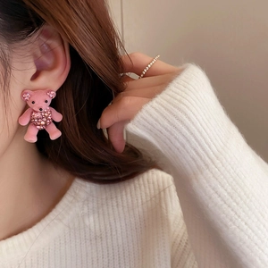 Close-up of a pink flocked bear earring with rhinestones worn by a model in profile
