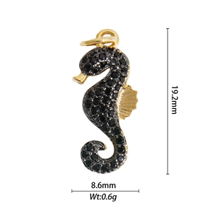 Detailed macro view of a gold-plated seahorse pendant with black stones, 19.2mm height