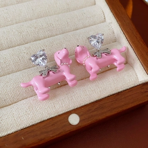 Close-up of pink puppy earrings with heart-shaped zircon and metal bow accents