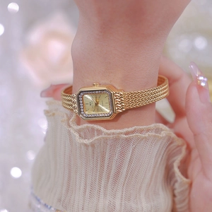Detailed macro view of an elegant gold square watch with crystal bezel and mesh band