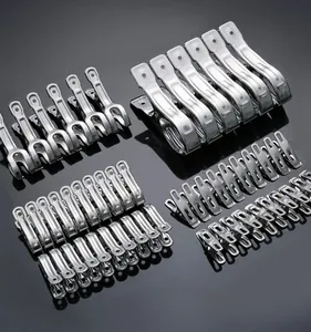 Macro detail of various sized stainless steel windproof clothespins arranged on a gray surface