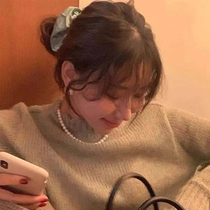 Close-up of a green fabric scrunchie in hair styled with a French pearl necklace