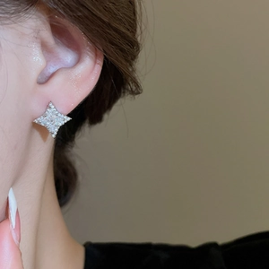 Close-up of a sparkling silver star-shaped earring with brilliant zircon on model ear