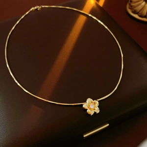 Dettaglio macro di una collana girocollo a fiore dorato su una scatola portaoggetti in pelle