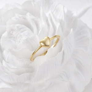 Detailed close-up of a minimalist gold heart ring nestled on a white textured flower