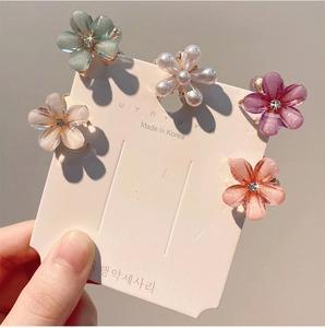 Détail macro de mini pinces à cheveux fleur en résine aux tons pastel avec petit diamant