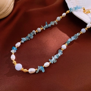 Detail of handmade aquamarine and pearl necklace on brown silk with gold clasp