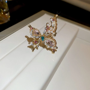 Macro shot of gold butterfly ring with pink gems, blue heart and white pearls