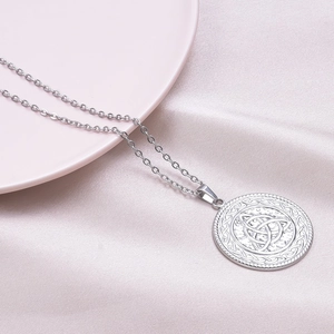 Detailed macro view of silver Celtic witch knot pendant on silk fabric background