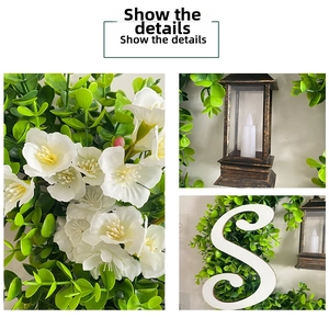 Detail of white artificial flowers, green leaves, and black vintage lantern with S letter