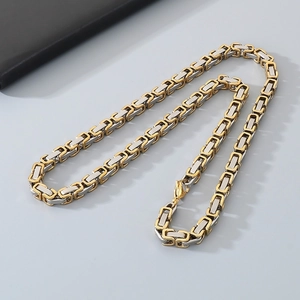 Macro detail of Byzantine steel chain necklace in gold and silver square link design