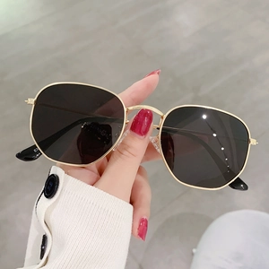 Detalle de cerca de las gafas de sol doradas irregulares con lentes poligonales oscuras