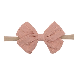 Detail of baby bow headband in dusty rose cotton linen with jacquard dotted texture