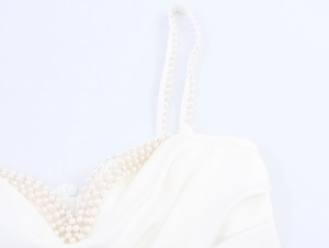 Close-up detail of elegant pearl beading on white satin dress neckline and straps