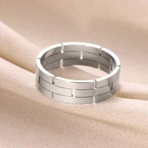 Macro view of silver geometric ring with brick texture on elegant satin fabric