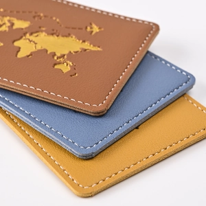 Detail view of stitched faux leather passport holders with gold world map and plane logo