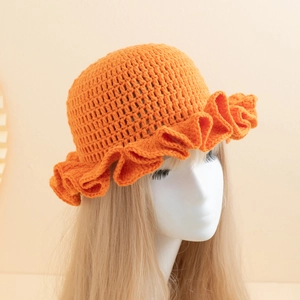 Detailed close-up of orange handmade crochet knit bucket hat with wavy ruffle edges