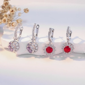 U-shaped earrings with purple and red gemstones on white stone background