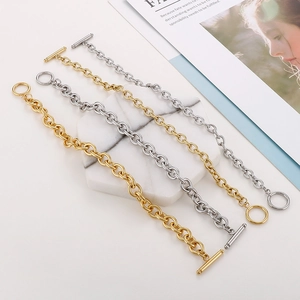 Detailed view of gold and silver OT buckle chain bracelets on a marble tray