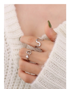 Detail of stacked silver heart and arrow rings on a soft white knit background