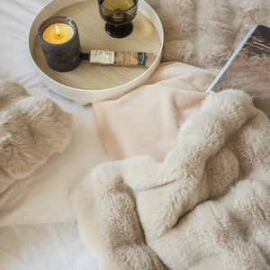 Close-up of soft beige faux fur blanket with plush texture in a luxury home setting