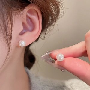 Close-up of minimalist pearl stud earrings worn by a model showing elegant luster
