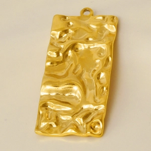Macro shot of gold-plated rectangle charm with hammered texture for DIY jewelry making