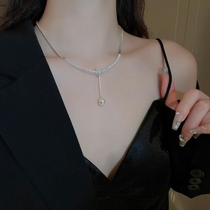 Dettaglio della collana d'argento con zirconi e pendente di perla bianca al collo
