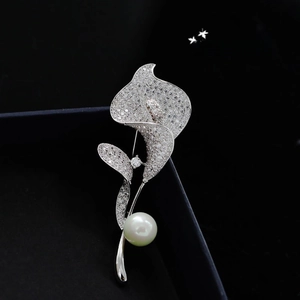Macro shot of silver calla lily brooch featuring pavé crystals and a lustrous white pearl