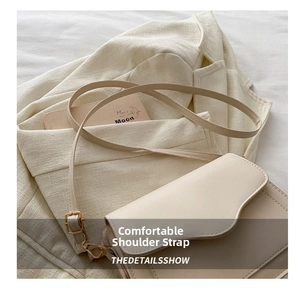 Detail of adjustable flat shoulder strap and golden hardware on beige crossbody bag