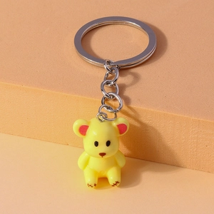 Detail view of yellow bear keychain with red accents on geometric display steps