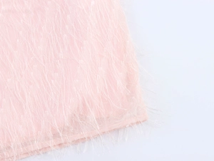 Dettaglio del tessuto con frange rosa chiaro e texture piumata dell'abito smanicato