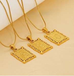 Detailed close-up of golden stainless steel square pendant necklaces with letter engravings
