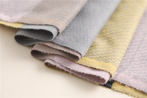 Detail of folded imitation cashmere scarves showing soft woven texture and fringe