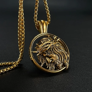Macro detail of a gold Jesus head pendant with thorn crown on a black textured surface