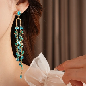 Detailed close-up of a long tassel earring with blue crystals and green turquoise beads