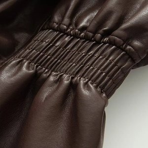 Détail de la taille élastique et de la texture en similicuir marron sur cette veste