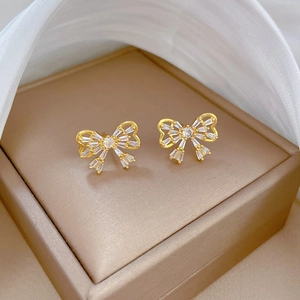 Macro view of crystal paved bow earrings in gold finish on a jewelry box