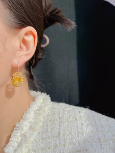 Close-up of elegant gold earrings with faceted yellow gemstones on a female model