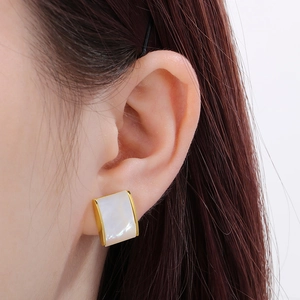 Detail of square shell stud earrings with gold plating on ear showing elegant scale