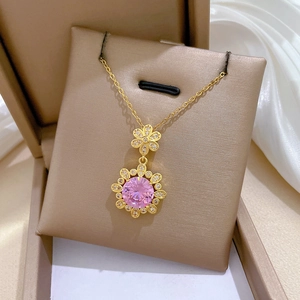 Macro shot of gold-plated sunflower pendant with pink crystal and sparkling diamonds